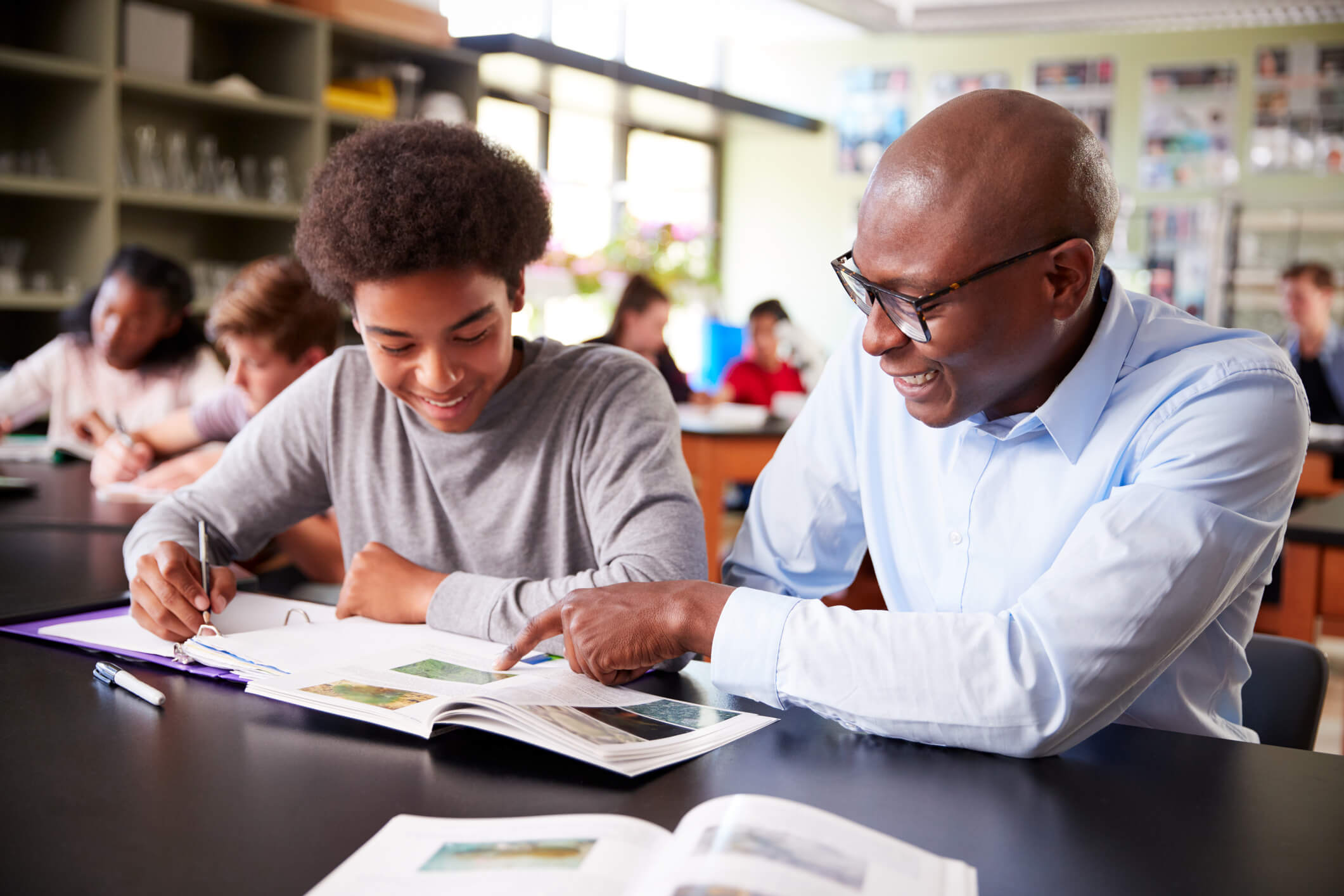 Teacher in classroom discussing materials with student